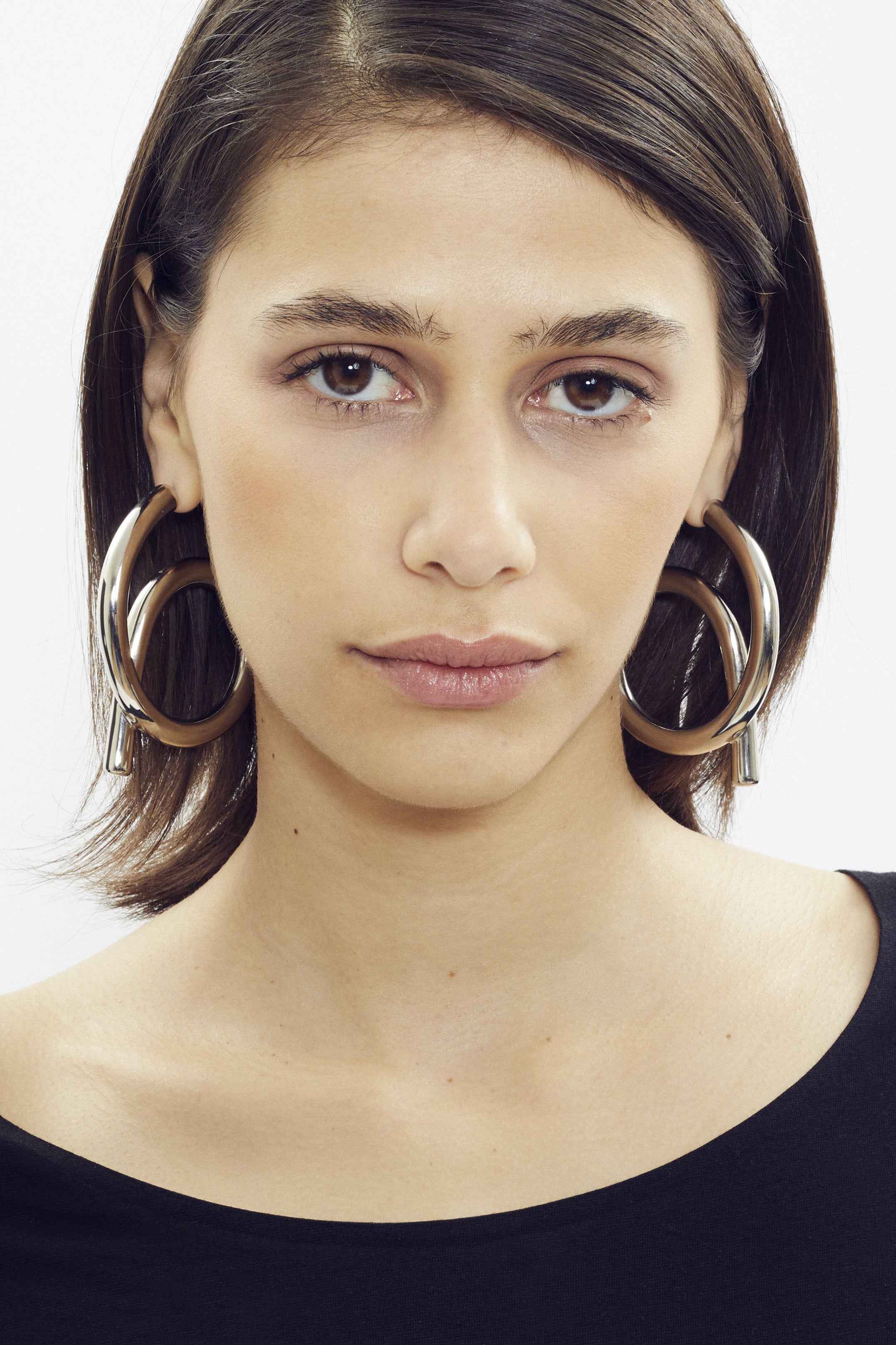 Large sculptural hoop earring with platinum finish by SONNEY, twisted tube shape